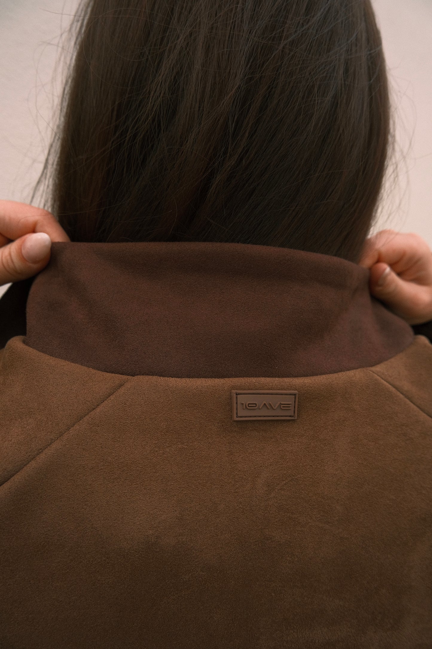 Detailed view of back collar on mocha brown women’s streetwear jacket – features ultra-soft brushed fabric and subtle rubber logo branding.