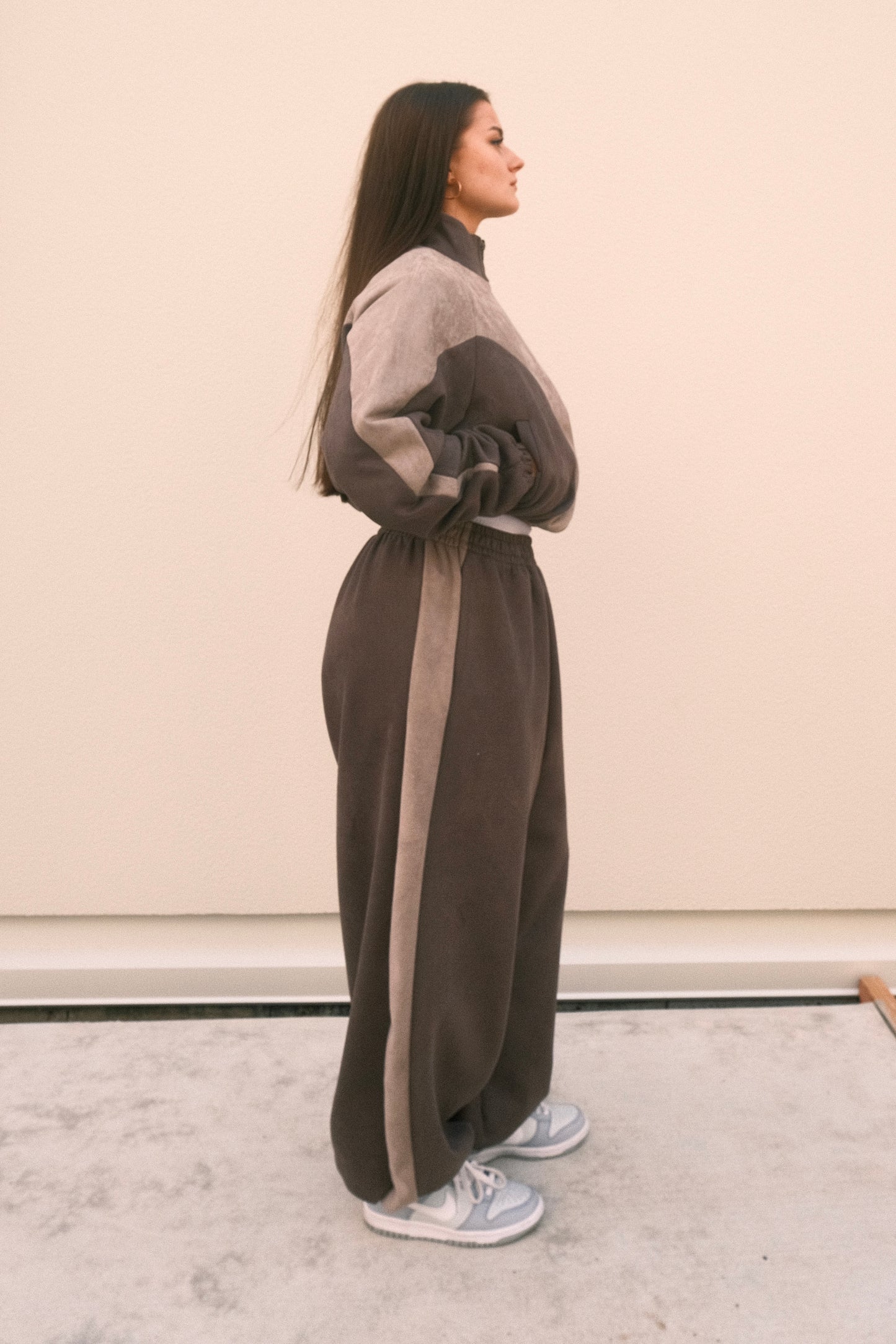 Model wearing ash grey oversized sweatpants with drawstring hem and wide waistband, paired with a matching cropped jacket – soft brushed texture, unisex one-size streetwear set.