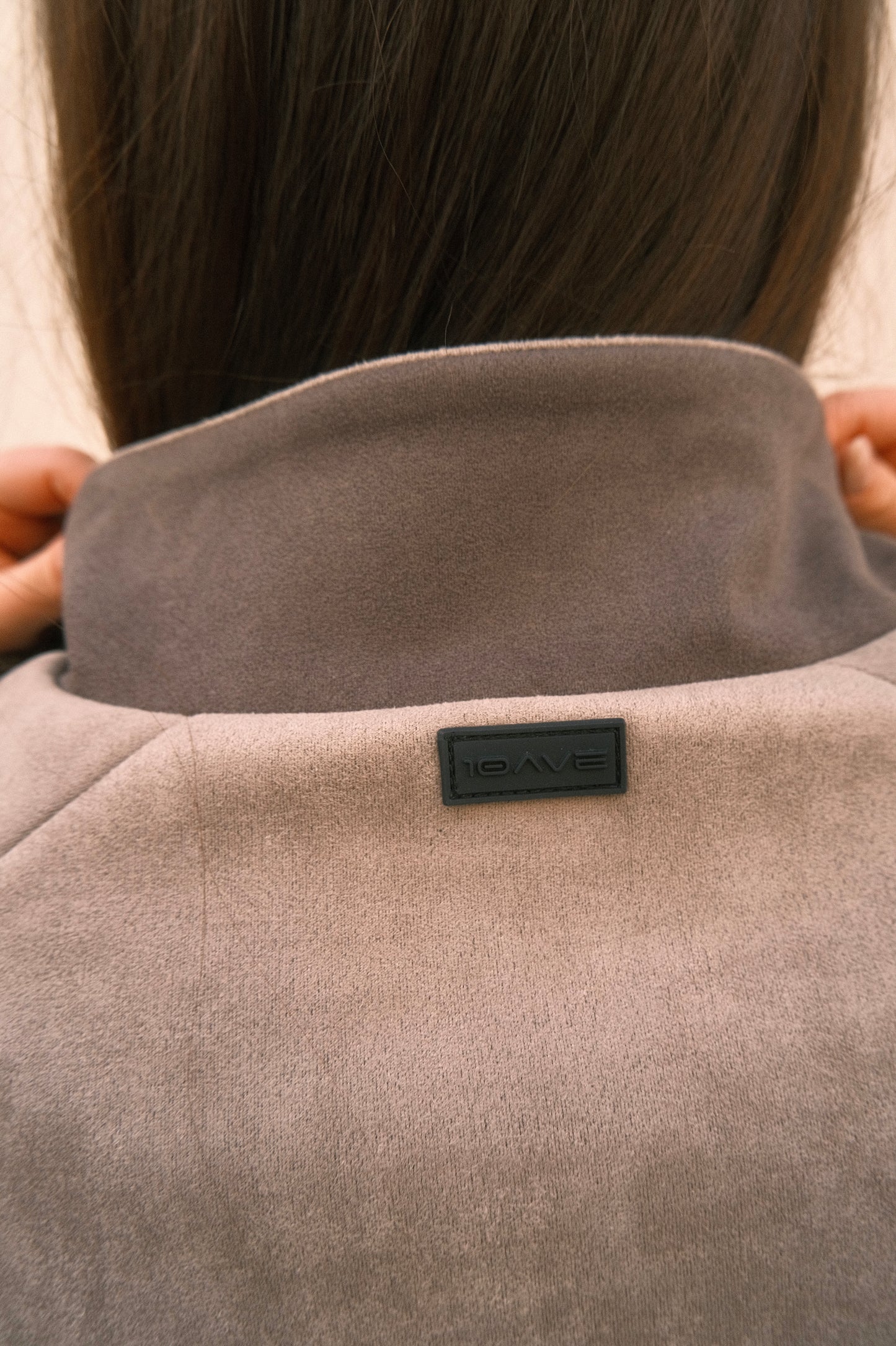 Detailed view of back collar on ash grey women’s streetwear jacket – features ultra-soft brushed fabric and subtle rubber logo branding.