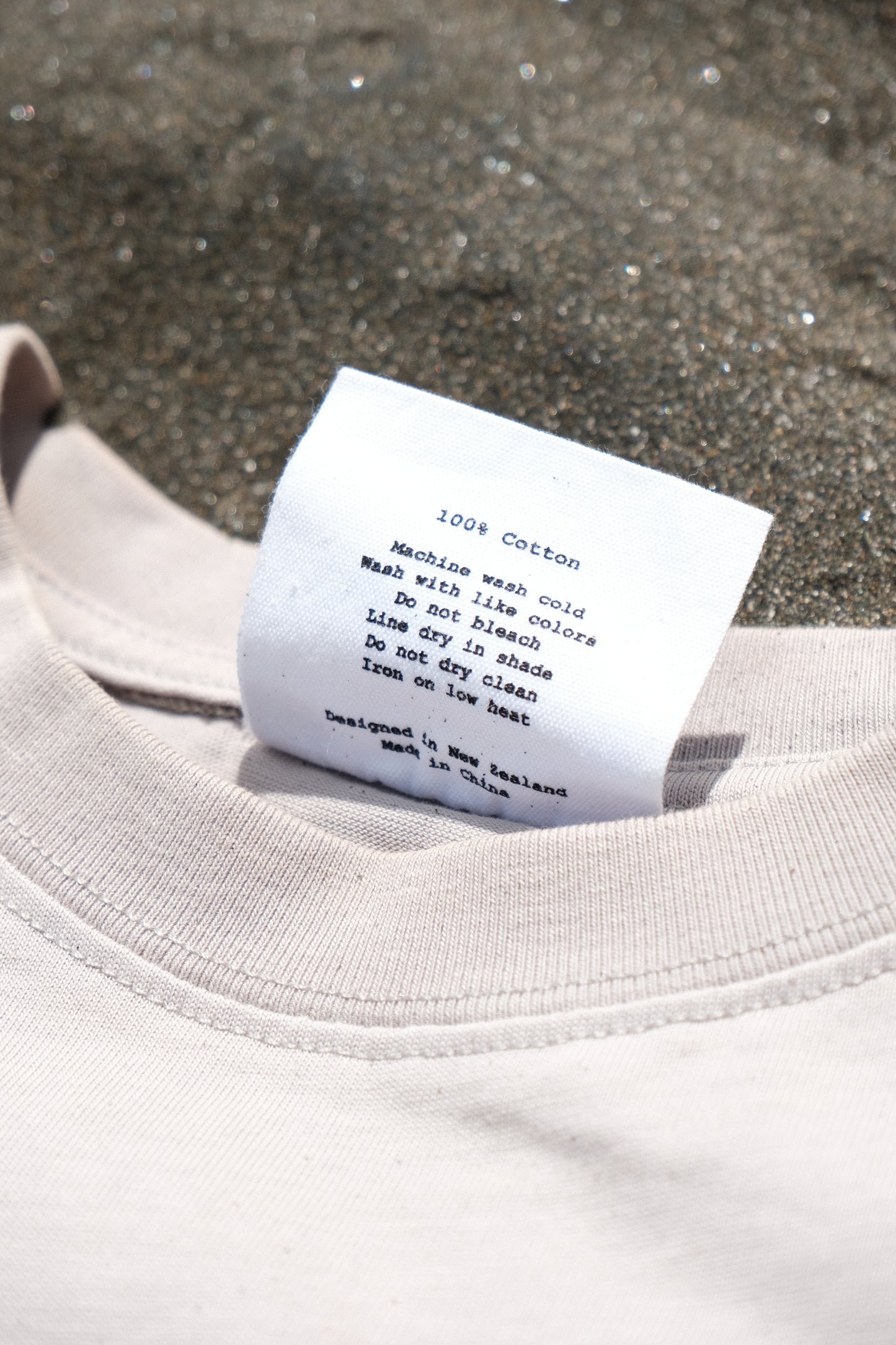 Close-up of a clothing tag on a light-colored garment against a textured background
