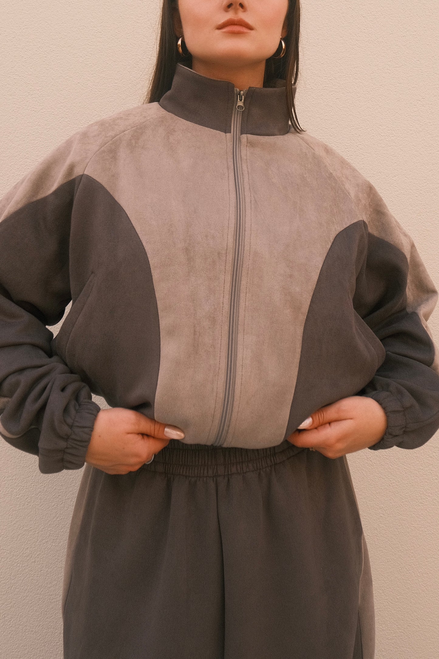 Cropped grey women’s streetwear jacket with front zipper, side pockets, and unique geometric cutouts – relaxed fit and soft brushed fabric.