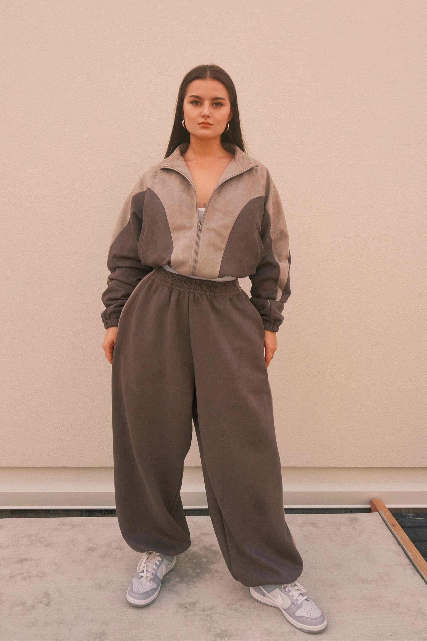 Women’s matching grey streetwear set featuring a cropped zip-up jacket with cutouts and logo, paired with oversized wide-leg sweatpants with adjustable drawstring hems – made from ultra-soft brushed poly-spandex blend for a cozy, elevated casual look.