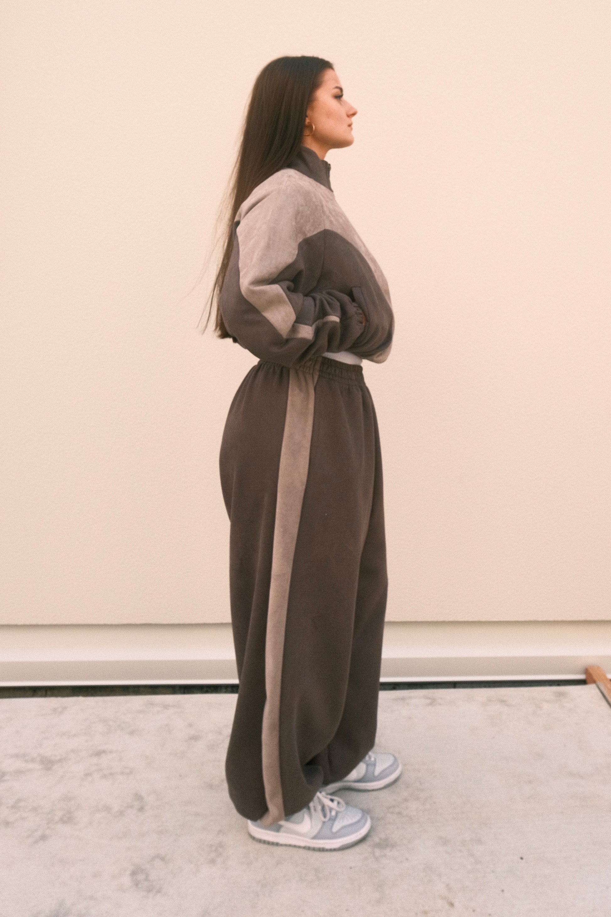 Model wearing ash grey oversized sweatpants with drawstring hem and wide waistband, paired with a matching cropped jacket – soft brushed texture, unisex one-size streetwear set.