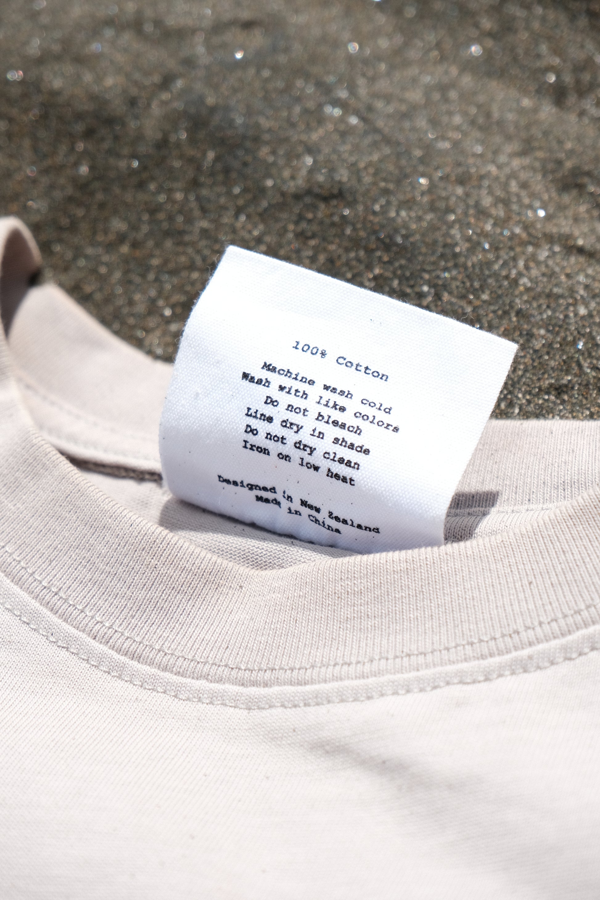 Close-up of a clothing tag on a light-colored garment against a textured background