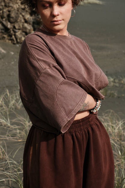 Person wearing a brown outfit standing in a natural setting