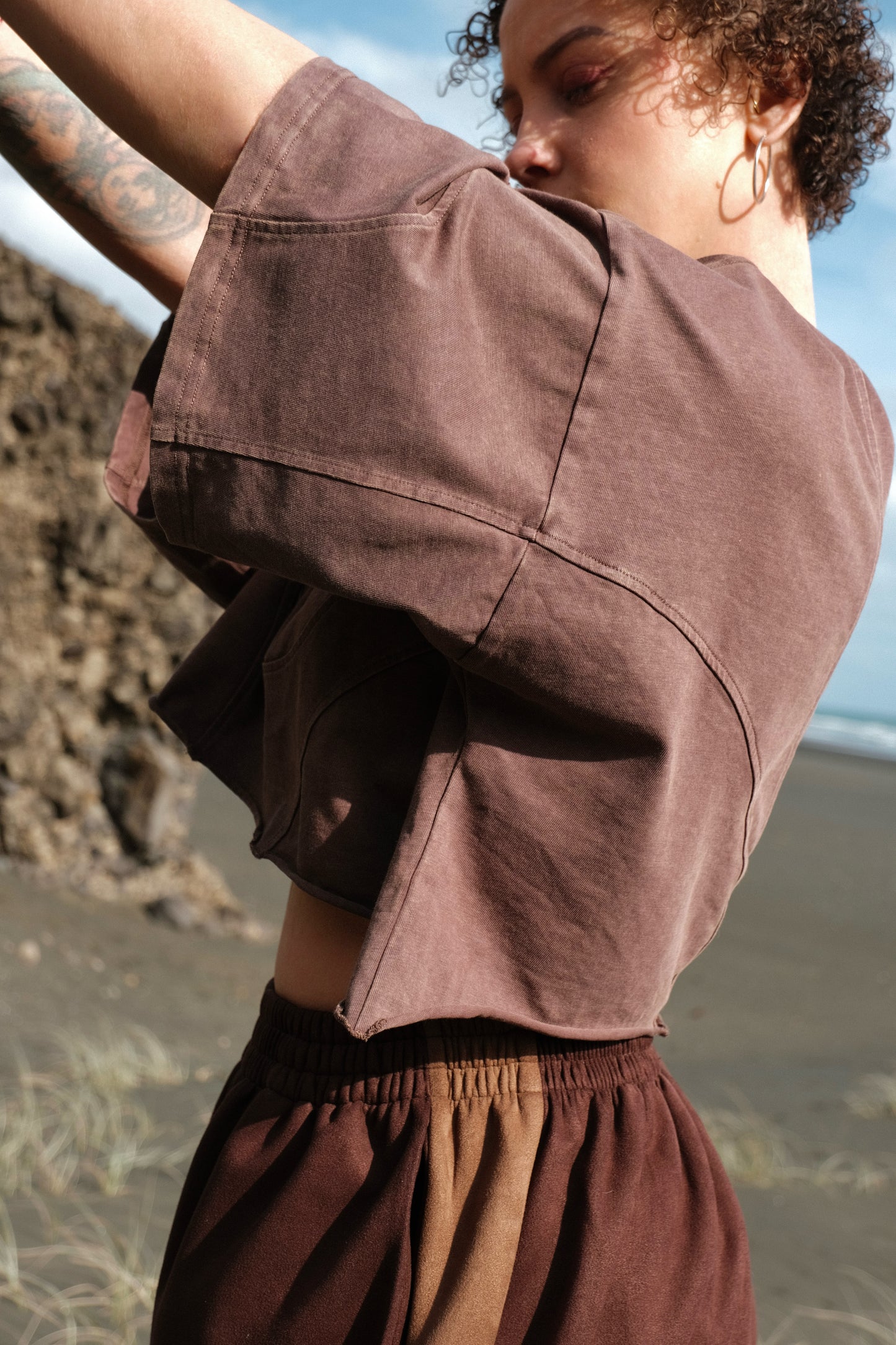 Person wearing a brown cropped tee on a beach
