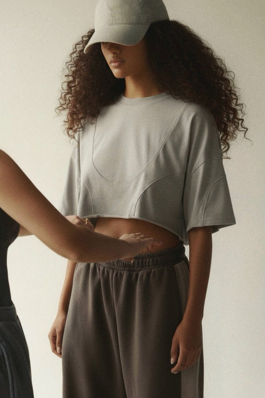 Model wearing the Gray Vintage Linework Tee with a grey cap and wide-leg pants, showing its cropped shape and curved stitching.