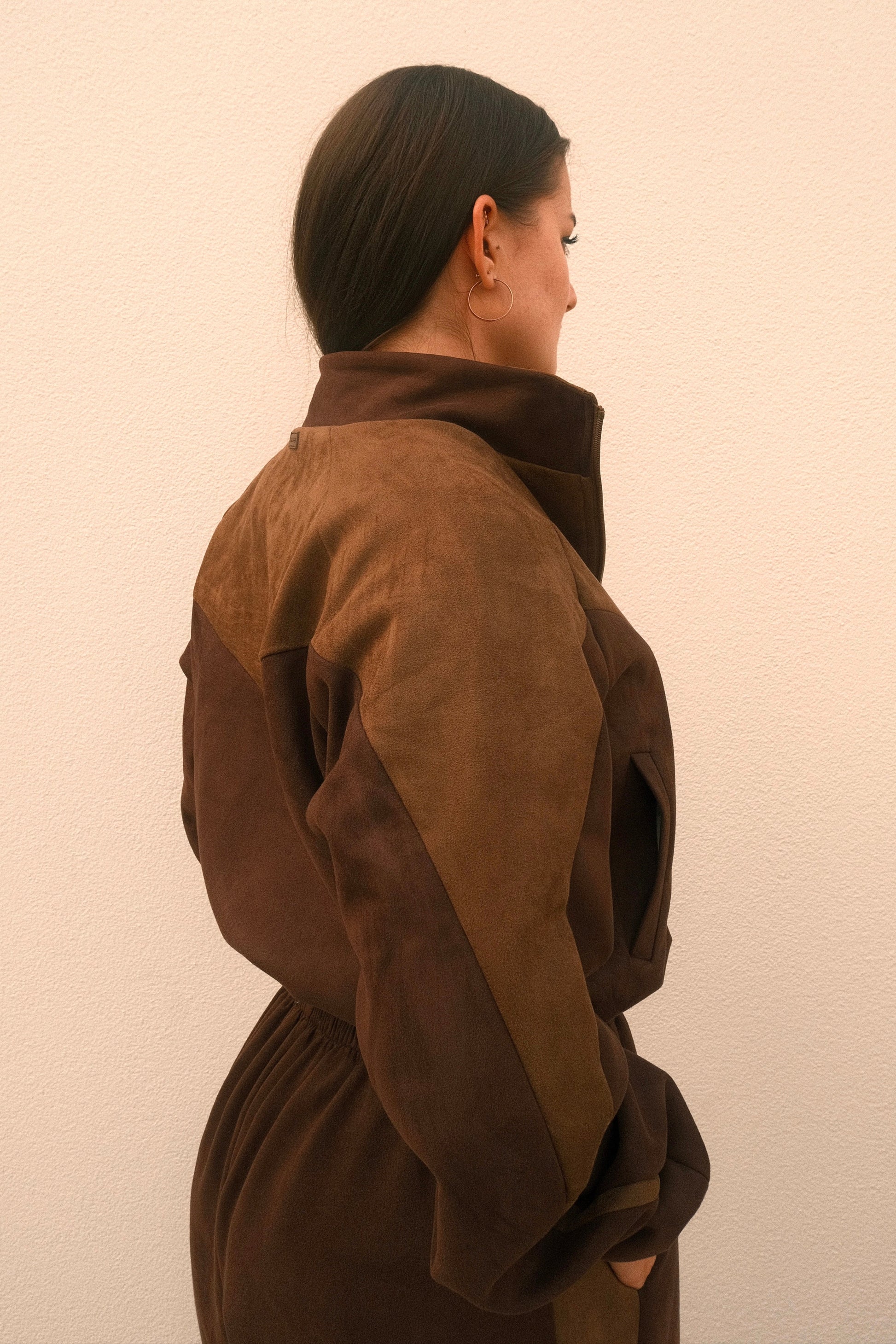 Cropped mocha brown women’s streetwear jacket with front zipper, side pockets, and unique geometric cutouts on the back – relaxed fit and soft brushed fabric.