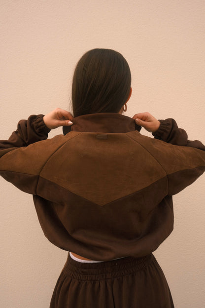 Cropped mocha brown women’s streetwear jacket with front zipper, side pockets, and unique geometric cutouts on the back – relaxed fit and soft brushed fabric.