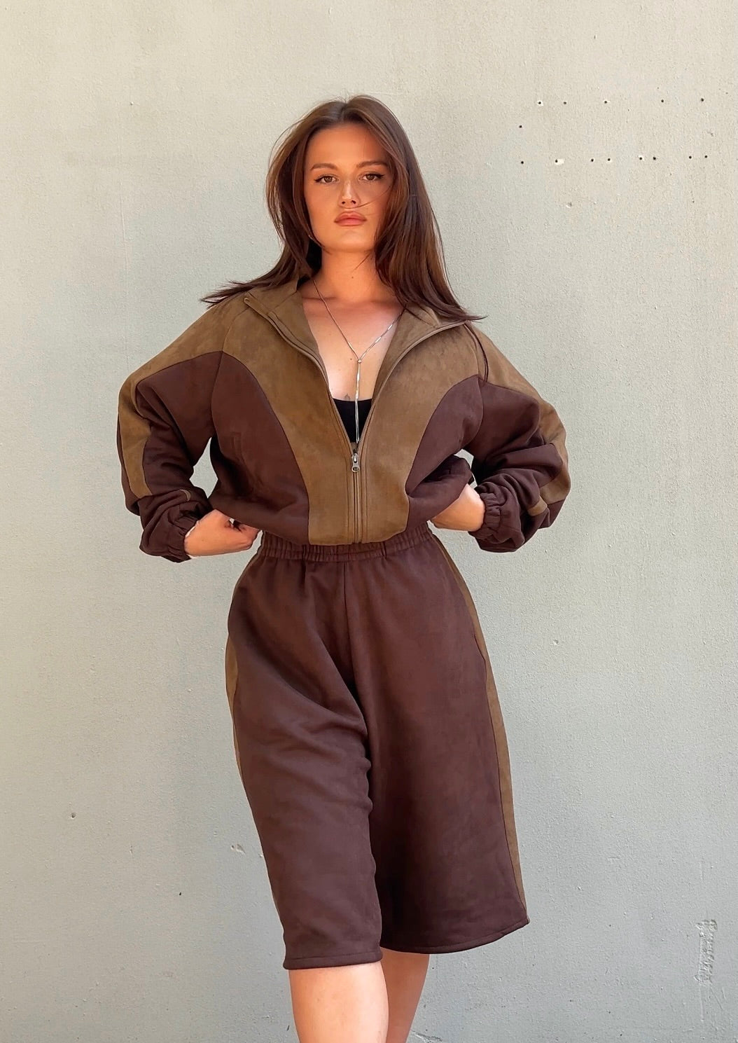 Woman wearing a brown tracksuit against a plain background